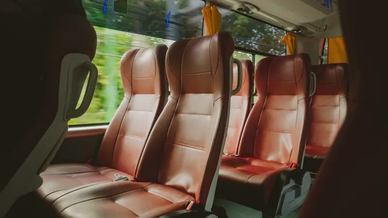Sièges en cuir vides à l'intérieur d'un autocar roulant le long d'une végétation
