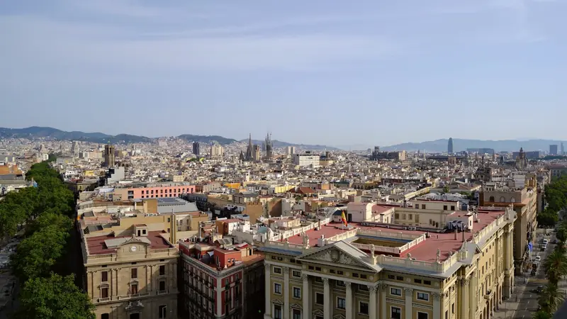 Vue en hauteur sur les toits de la vieille ville de Barcelone, avec la Sagrada Família et les collines au loin
