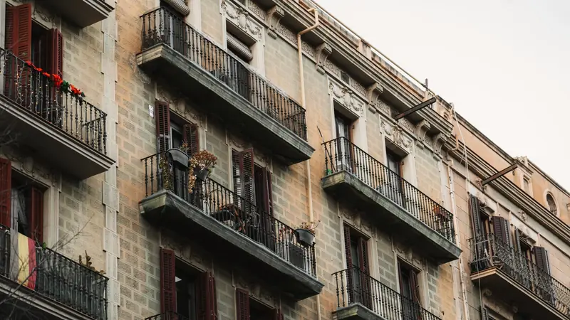 Façade d'un immeuble ancien de Barcelone avec balcons en fer forgé et volets bordeaux