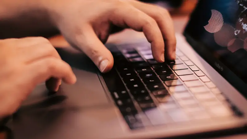 Mains tapant sur le clavier rétroéclairé d'un ordinateur portable