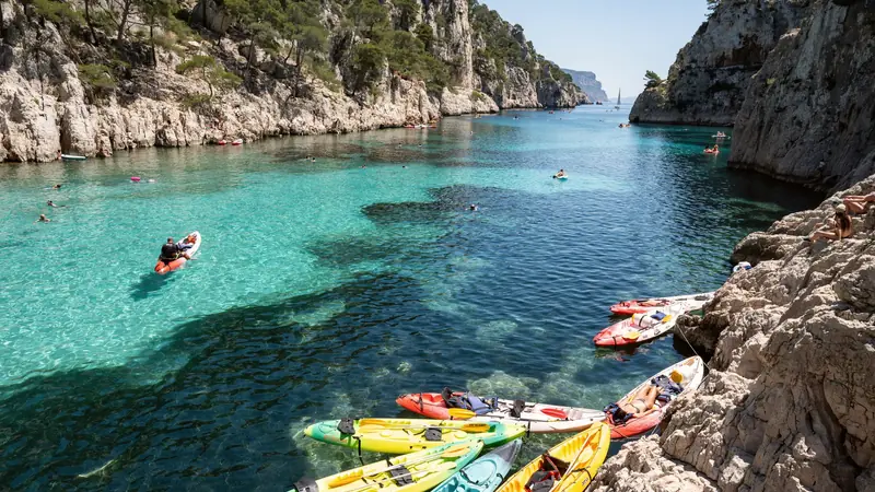 Kayaks colorés amarrés sur les rochers d'une calanque marseillaise à l'eau turquoise