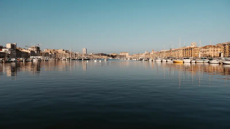 Bassin du Vieux-Port de Marseille au calme, voiliers amarrés le long des quais et façades dorées par le soleil