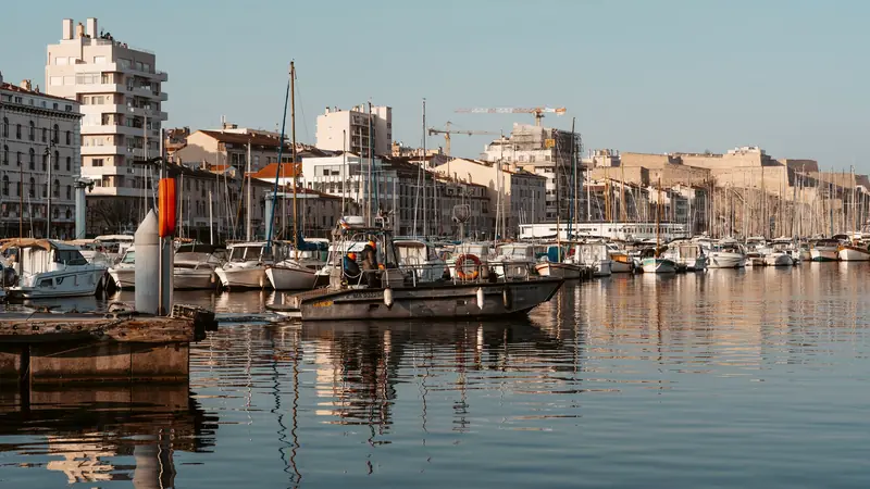 Barques de pêche et bateaux amarrés dans un port de Marseille au soleil du matin