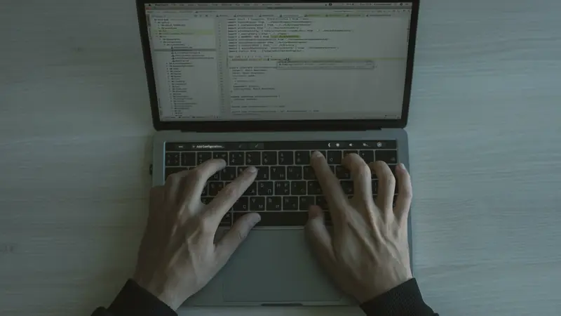 Vue de dessus de deux mains tapant sur un ordinateur portable ouvert sur un éditeur de code